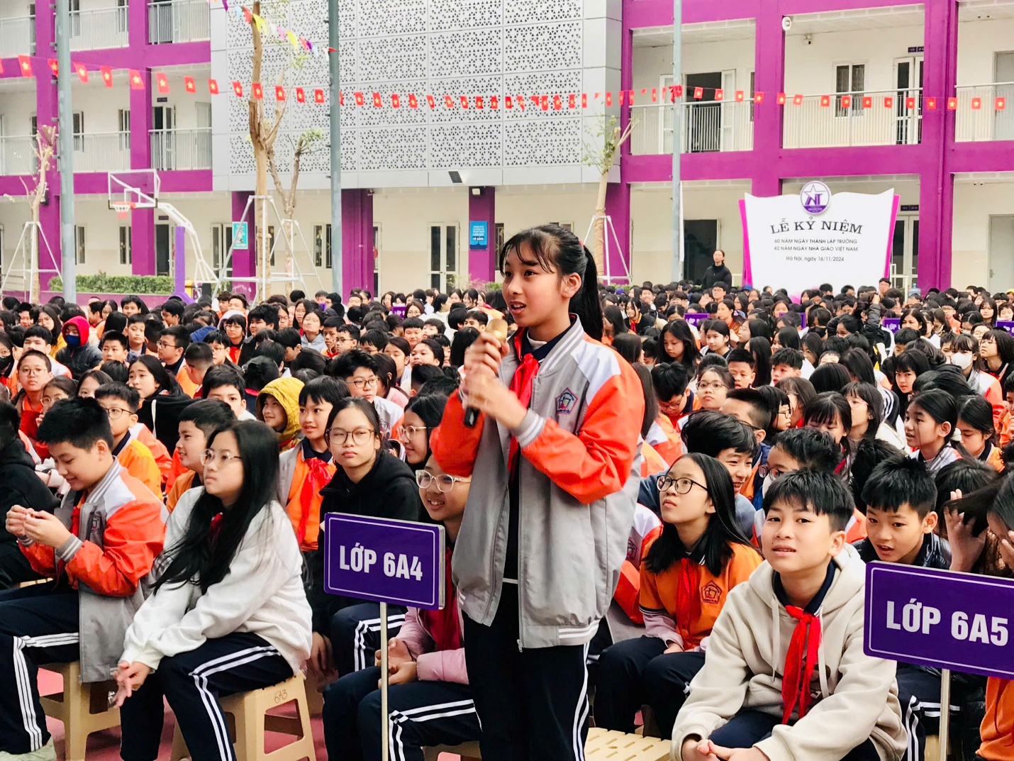 A child speaking into a microphone in front of a large crowd of people

Description automatically generated